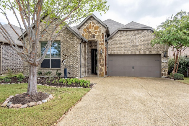 view of front facade featuring an attached garage, stone siding, driveway, and brick siding