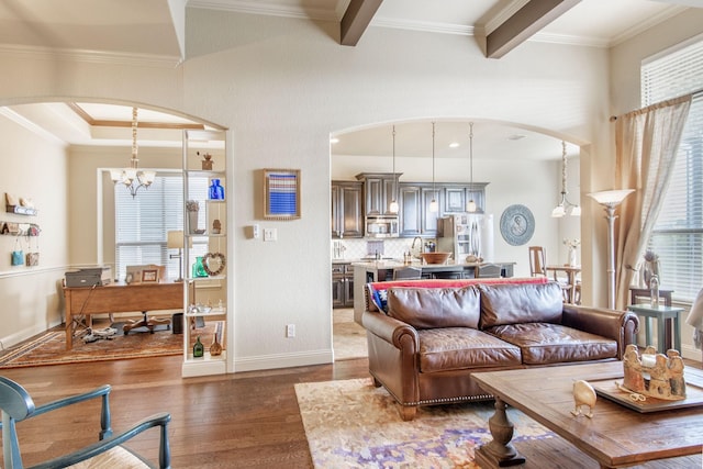 living room with a healthy amount of sunlight, an inviting chandelier, dark wood-style floors, and arched walkways