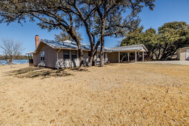 ranch-style house with a carport, a front yard, and a chimney