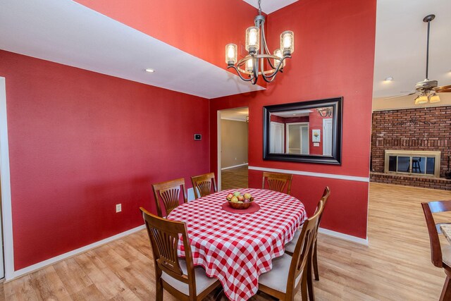 dining space featuring a brick fireplace, wood finished floors, and baseboards