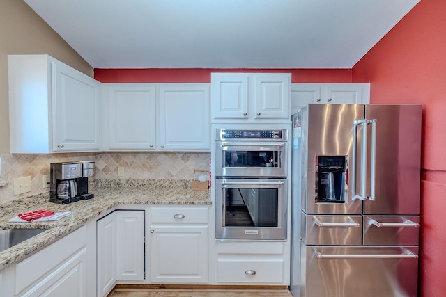 kitchen with white cabinetry, backsplash, and appliances with stainless steel finishes