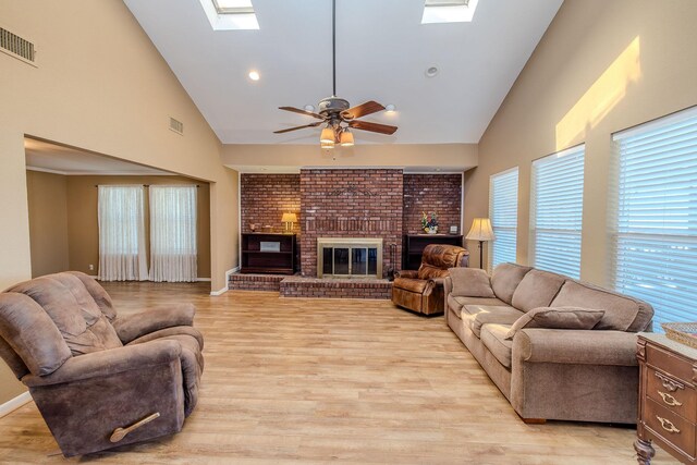 living room with light wood-style floors, a skylight, a fireplace, and visible vents