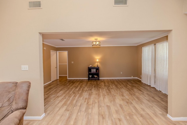 unfurnished living room featuring visible vents, light wood-type flooring, baseboards, and ornamental molding