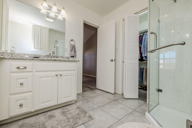 bathroom featuring tile patterned flooring, a shower stall, vanity, and a walk in closet