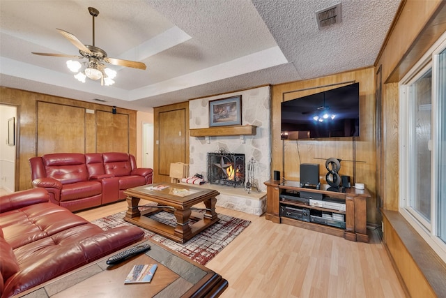 living area with visible vents, wood walls, a tray ceiling, wood finished floors, and a textured ceiling