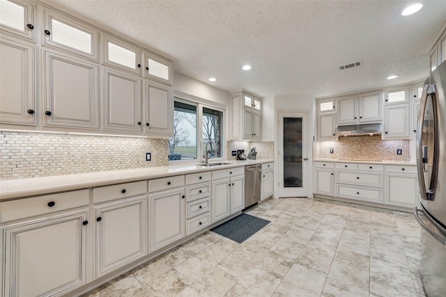 kitchen featuring visible vents, backsplash, light countertops, appliances with stainless steel finishes, and a sink