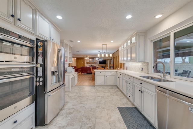 kitchen featuring a sink, appliances with stainless steel finishes, open floor plan, and white cabinetry