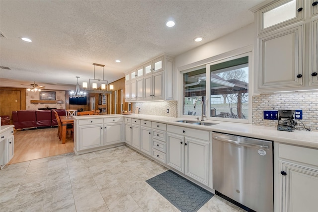 kitchen featuring a sink, open floor plan, a peninsula, light countertops, and dishwasher