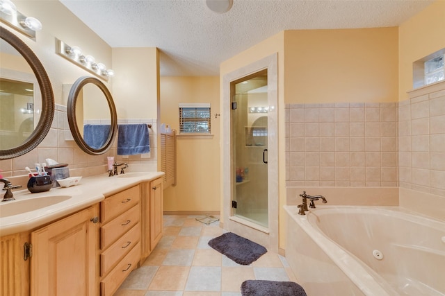 full bath featuring a stall shower, a whirlpool tub, a sink, a textured ceiling, and tile walls