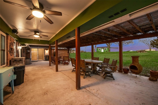 patio terrace at dusk featuring outdoor dining area, a ceiling fan, a pergola, and a yard