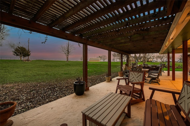 patio terrace at dusk featuring a pergola and a yard