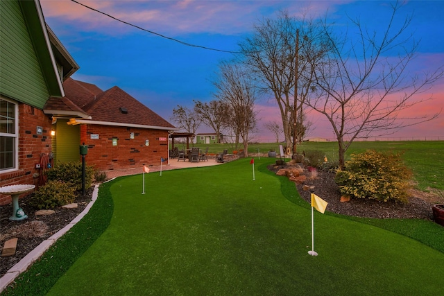 yard at dusk featuring a patio area