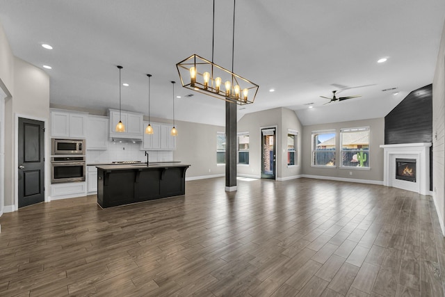 kitchen with a ceiling fan, a glass covered fireplace, open floor plan, stainless steel appliances, and white cabinets