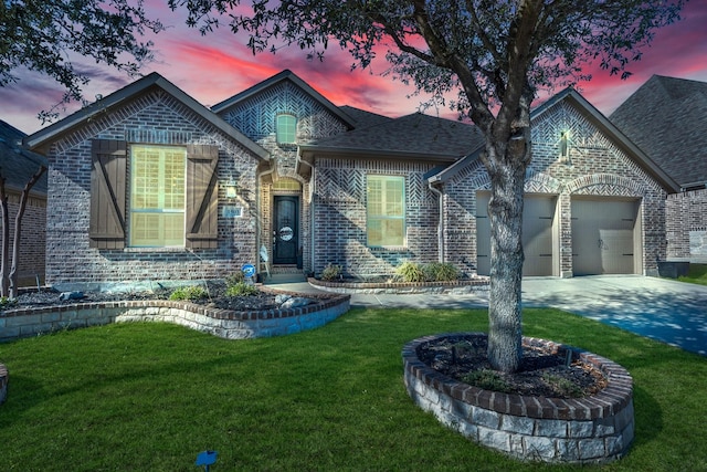 french country home featuring brick siding, a shingled roof, a front yard, a garage, and driveway