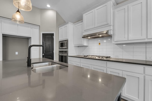 kitchen with a sink, white cabinets, appliances with stainless steel finishes, dark countertops, and tasteful backsplash