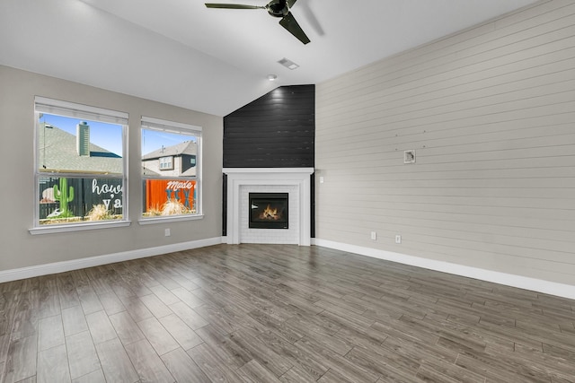 unfurnished living room with a ceiling fan, wood finished floors, a fireplace, baseboards, and vaulted ceiling