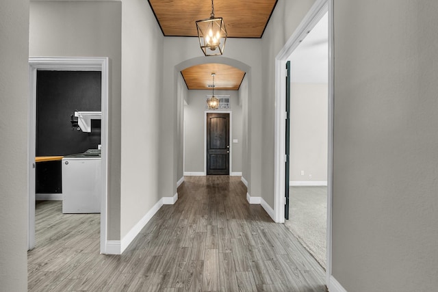 hallway featuring wood finished floors, baseboards, an inviting chandelier, arched walkways, and wood ceiling