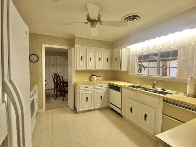 kitchen with visible vents, a sink, white appliances, white cabinets, and light countertops