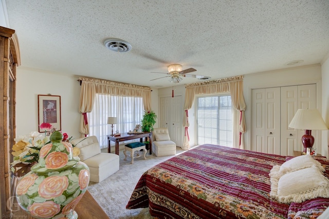 carpeted bedroom with visible vents, multiple windows, and a textured ceiling