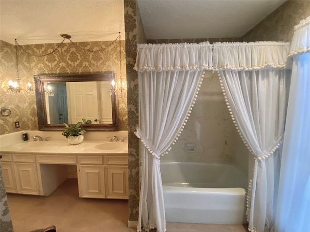 bathroom featuring a sink, a textured ceiling, double vanity, and wallpapered walls