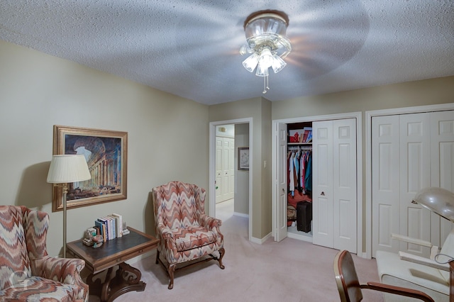 sitting room with baseboards, light carpet, a textured ceiling, and a ceiling fan