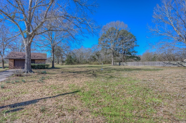 view of yard featuring an outbuilding, an attached garage, and fence