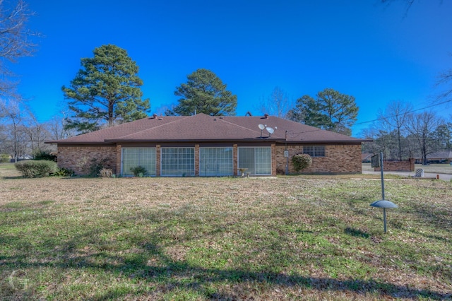 rear view of house with a yard, brick siding, and a garage