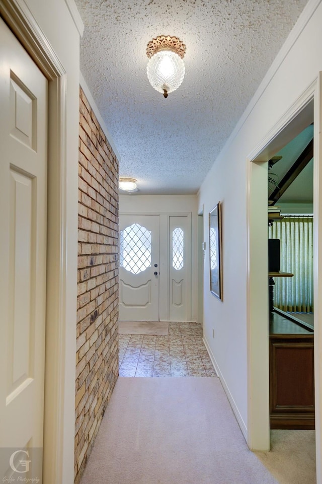 carpeted foyer with tile patterned floors, a textured ceiling, and brick wall