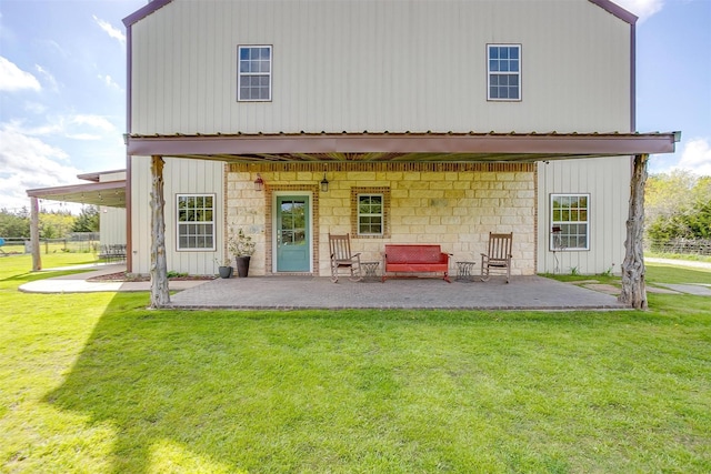 rear view of property featuring a patio area, board and batten siding, and a yard