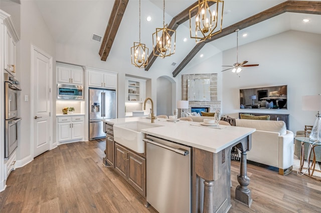 kitchen featuring stainless steel appliances, visible vents, open floor plan, a sink, and wood finished floors