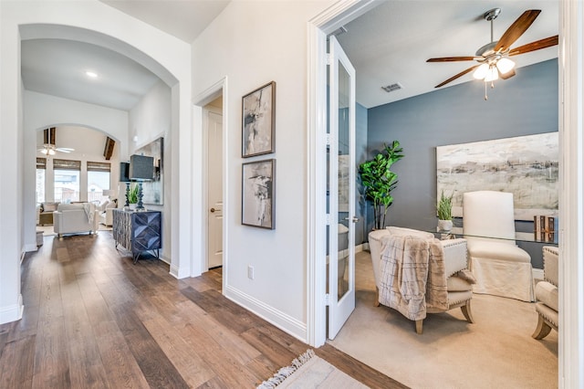 hallway with baseboards, visible vents, arched walkways, lofted ceiling, and wood finished floors