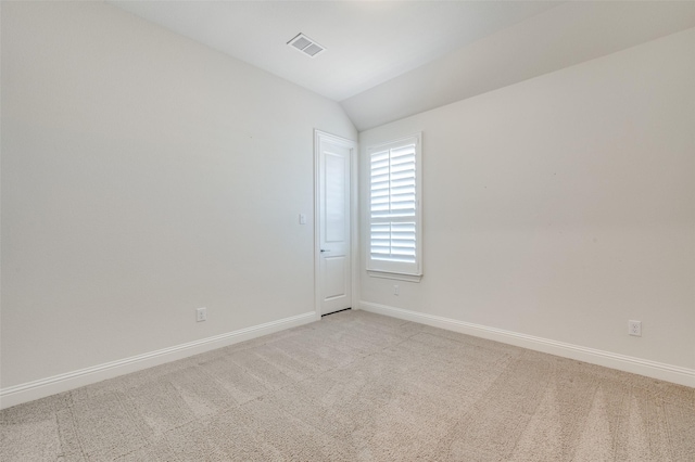 unfurnished room with visible vents, vaulted ceiling, light carpet, and baseboards