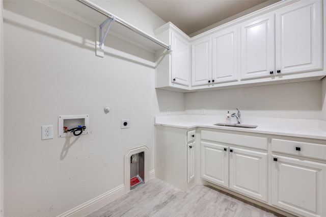 washroom with hookup for an electric dryer, washer hookup, a sink, light wood-type flooring, and cabinet space