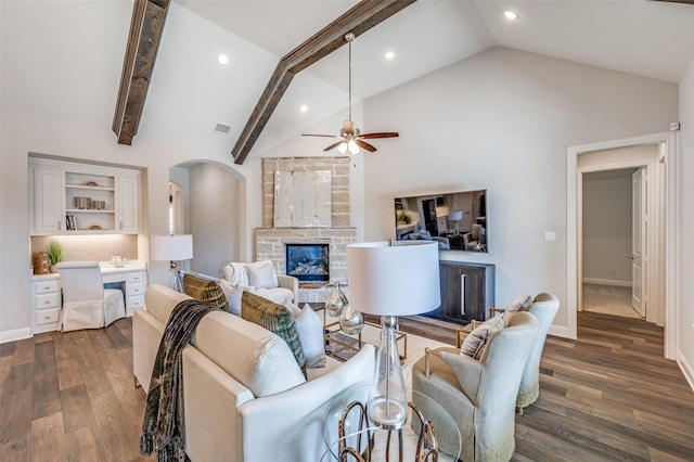 living area featuring visible vents, arched walkways, built in study area, dark wood-style flooring, and a stone fireplace