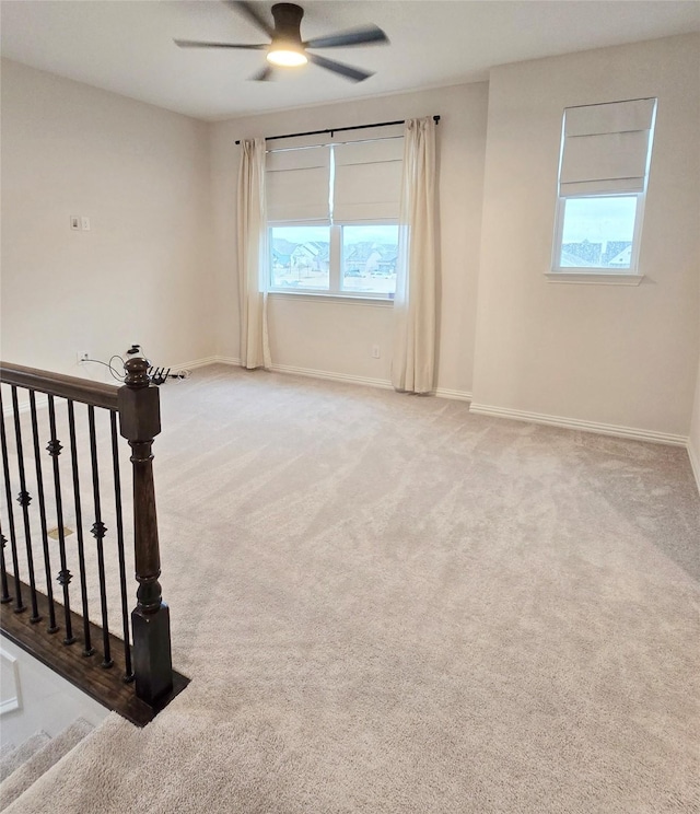 empty room featuring a healthy amount of sunlight, light colored carpet, and baseboards