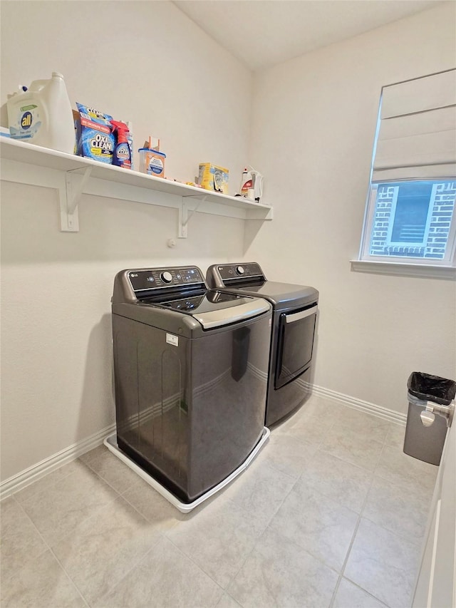 clothes washing area featuring laundry area, washer and clothes dryer, baseboards, and light tile patterned floors