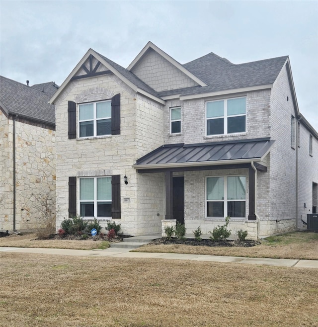 craftsman house featuring a standing seam roof, a shingled roof, a front yard, and brick siding