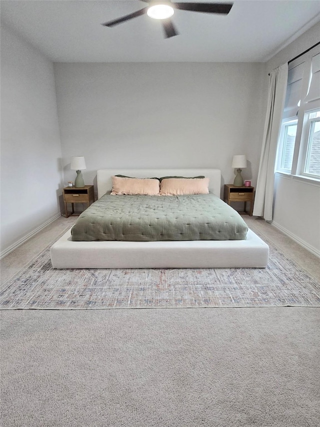 carpeted bedroom with ceiling fan and baseboards