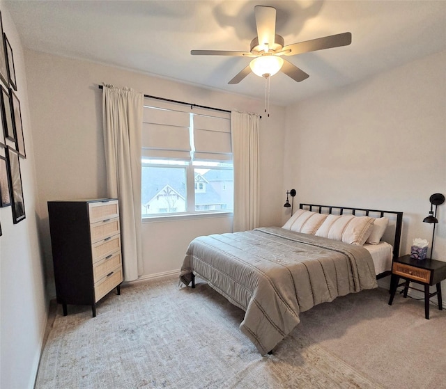 bedroom with ceiling fan, baseboards, and light colored carpet