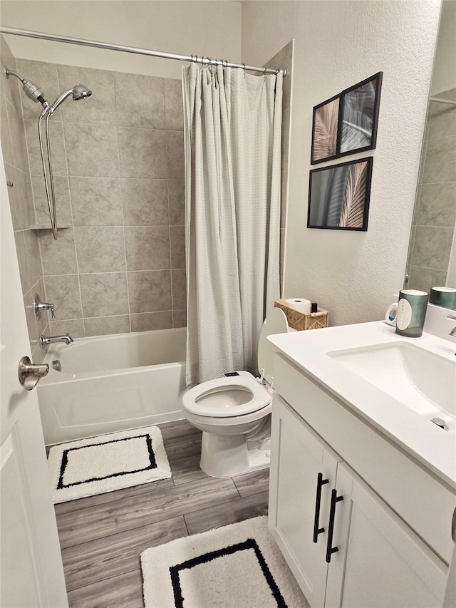 full bath with a textured wall, shower / bathtub combination with curtain, toilet, vanity, and wood finished floors