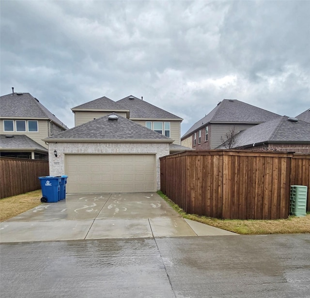 view of front of property featuring a shingled roof, concrete driveway, fence, and an attached garage