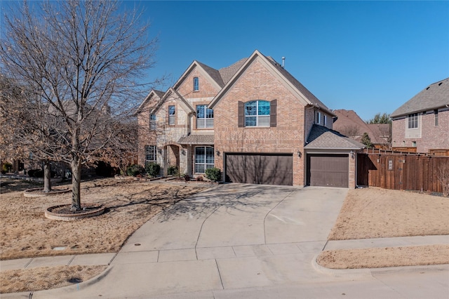 view of front facade featuring a garage, brick siding, driveway, and fence