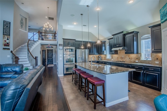 kitchen featuring a breakfast bar area, visible vents, a sink, appliances with stainless steel finishes, and tasteful backsplash