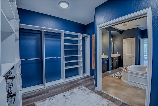 full bathroom with baseboards, wood finished floors, a garden tub, a textured wall, and vanity