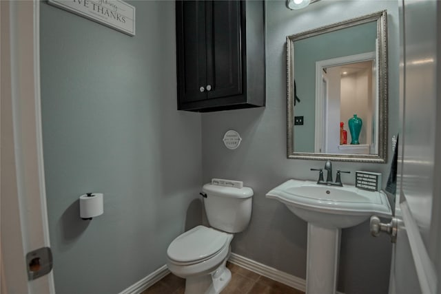 bathroom featuring toilet, baseboards, and a sink