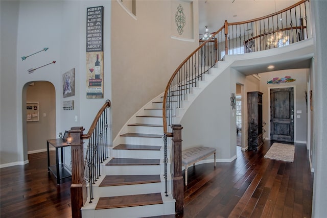 stairway featuring baseboards, arched walkways, and hardwood / wood-style flooring