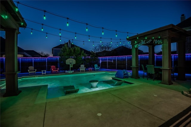 pool at twilight featuring a patio area, a fenced in pool, and fence