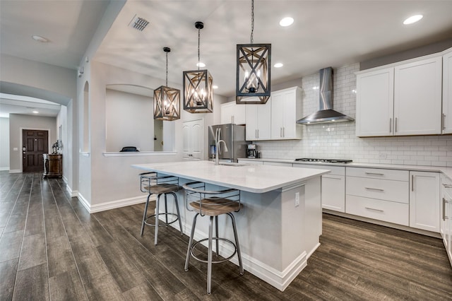 1121 Ash St, Celina, TX 75009 - kitchen featuring a breakfast bar, decorative backsplash, dark wood-style floors, wall chimney exhaust hood, and a center island with sink