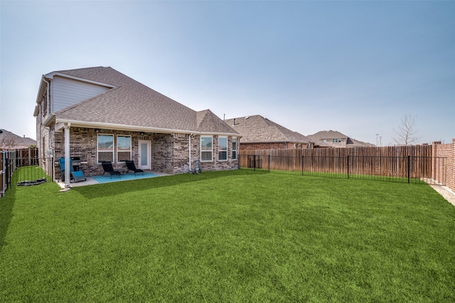 1121 Ash St, Celina, TX 75009 - rear view of house with a fenced backyard, brick siding, a yard, roof with shingles, and a patio area