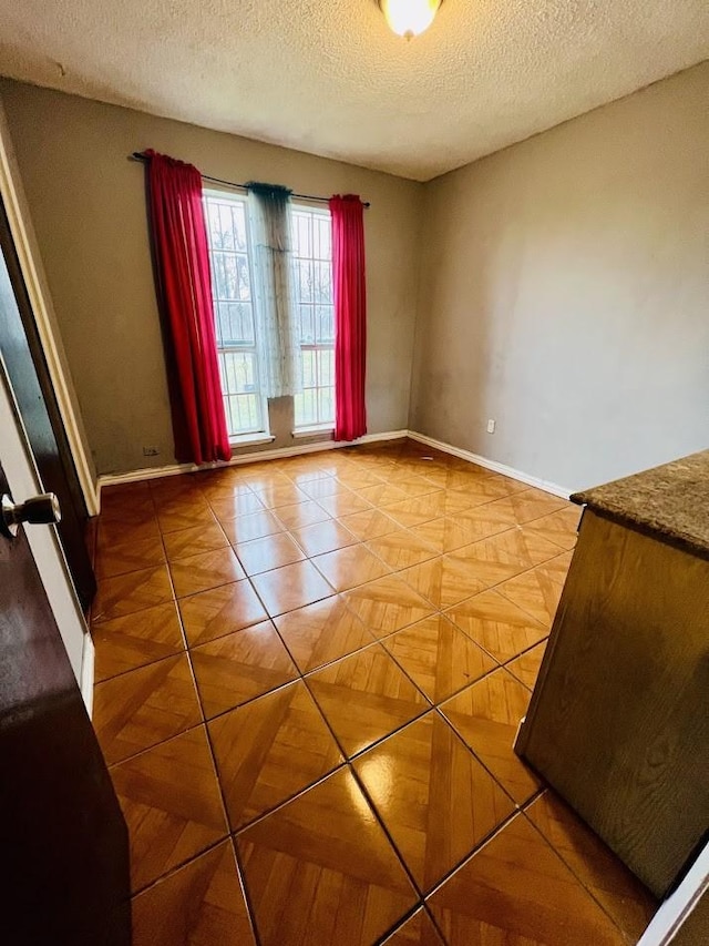 unfurnished room featuring a textured ceiling and baseboards